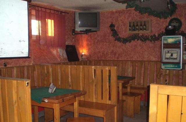 Historický interiér s drevenými lavicami a nástenným jukeboxom vpravo
