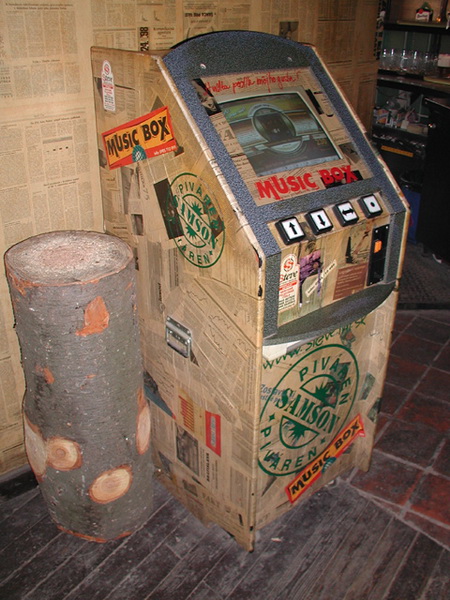 Jukebox s novinovým dekorom pri stene s rovnakým motívom